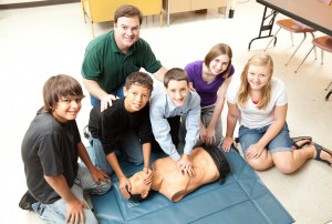 A group of teenage students learning CPR life saving techniques in class.